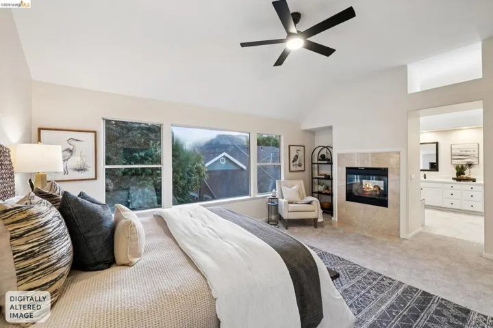 Bedroom with ensuite bath, carpet flooring, lofted ceiling, a fireplace, and a ceiling fan