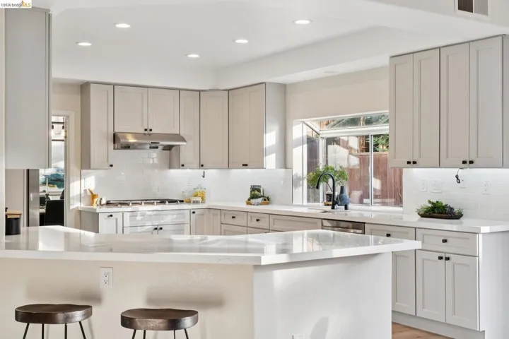 Kitchen with recessed lighting, decorative backsplash, light stone countertops, a kitchen breakfast bar, and stainless steel dishwasher