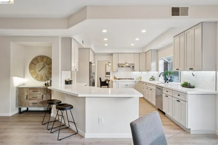 Kitchen featuring backsplash, a peninsula, a breakfast bar area, recessed lighting, and light wood finished floors