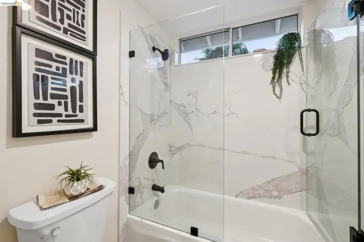 Full bath with toilet and shower / bath combination with glass door