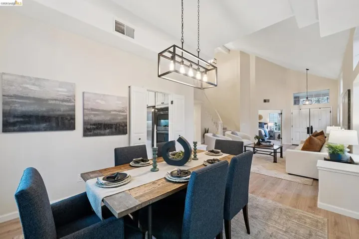 Dining space featuring light wood-type flooring, vaulted ceiling, and suspended lighting