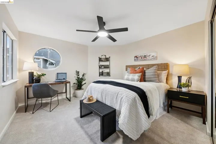 Bedroom with an office area, light colored carpet, and a ceiling fan