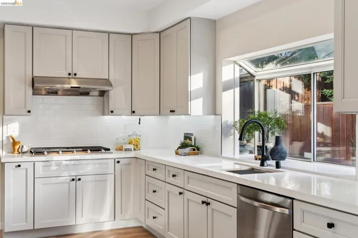 Kitchen with light stone counters, dishwasher, light wood finished floors, and decorative backsplash