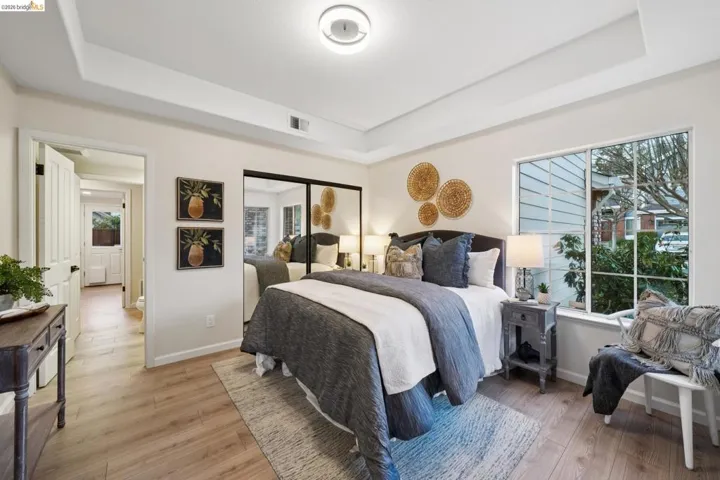 Bedroom featuring a tray ceiling, a closet, and light wood finished floors