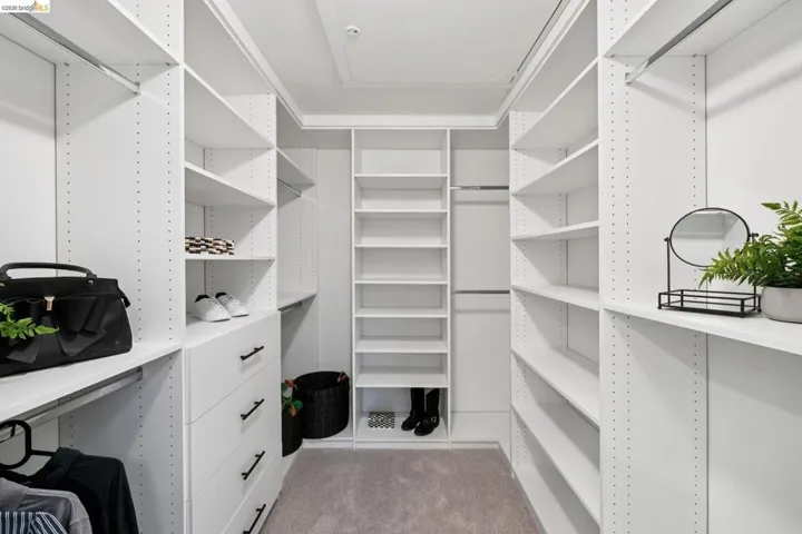 Walk in closet with light colored carpet and light tile patterned flooring