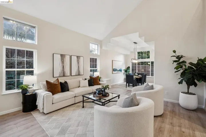 Living room featuring light wood-style flooring, vaulted ceiling, and plenty of natural light