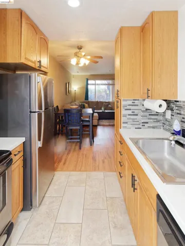 Kitchen featuring open floor plan, light countertops, stainless steel appliances, light tile patterned flooring, and light wood finish cabinetry
