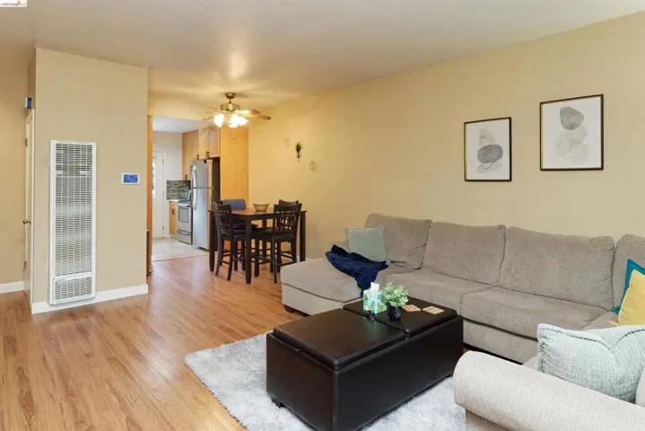 Living area featuring a heating unit, light wood finished floors, and a ceiling fan