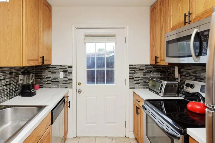 Kitchen with stainless steel appliances, light tile patterned floors, and wood finish cabinets