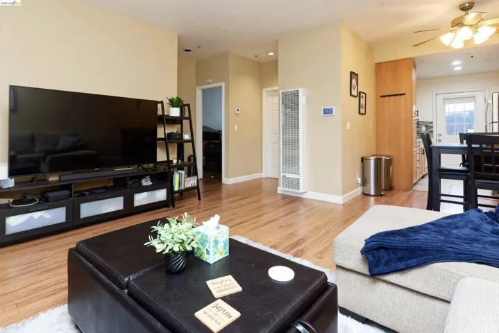 Living room featuring light wood-style flooring, a ceiling fan, a heating unit, and recessed lighting