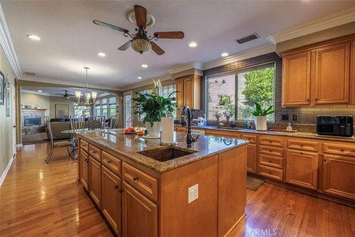 Spacious kitchen has granite counters, a center island with sink, lots of cabinetry with plenty of storage, recessed lighting, and hardwood flooring. Kitchen is open to the family room and dining area.