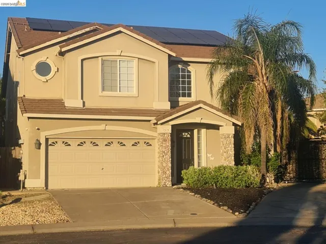 View of front of house featuring solar panels, a tiled roof, and driveway