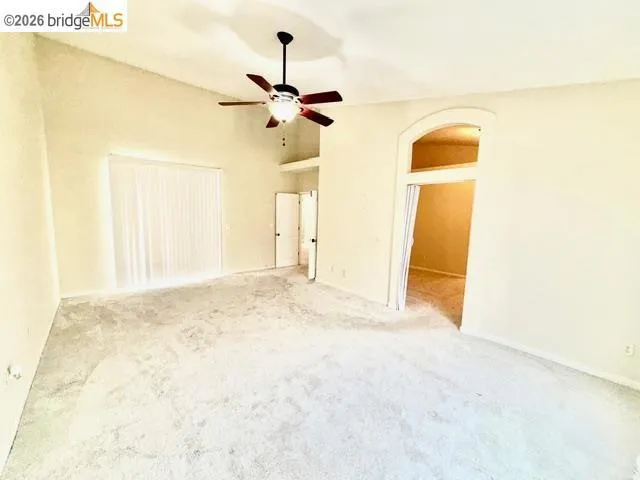 Spare room with light carpet, arched walkways, and ceiling fan