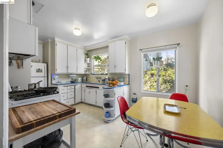 Kitchen with open shelves, light floors, white cabinets, backsplash, and freestanding refrigerator
