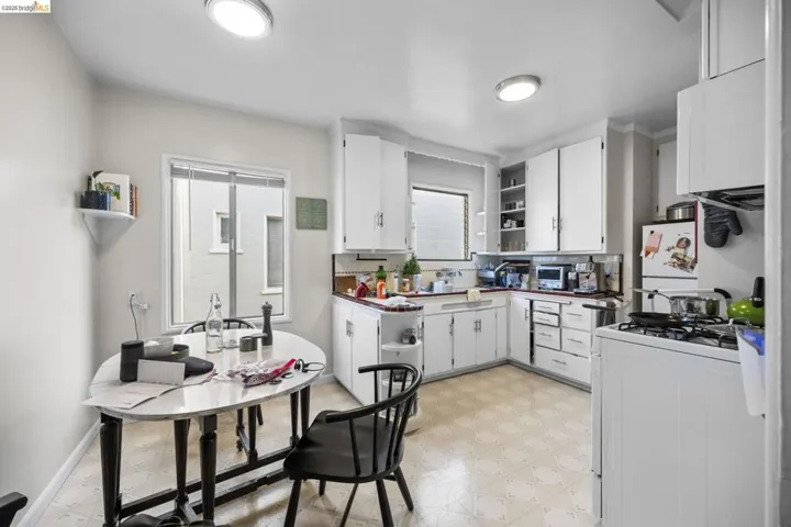 Kitchen with open shelves, light flooring, white appliances, and white cabinetry