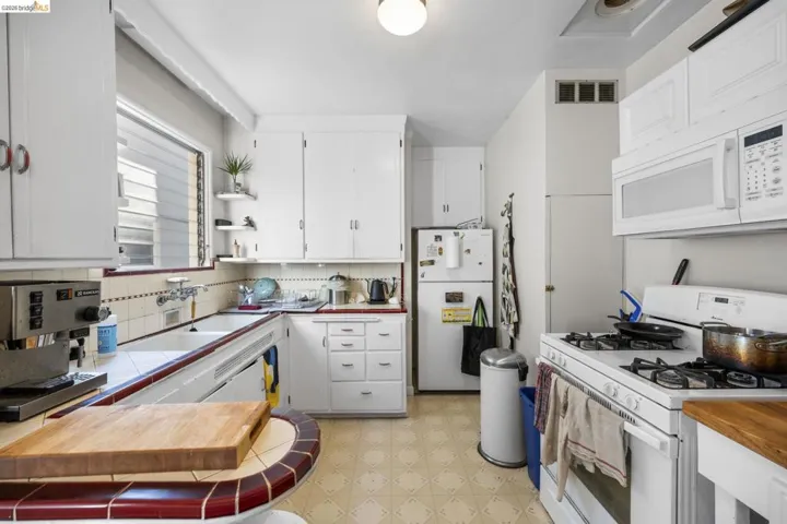 Kitchen with white appliances, light flooring, open shelves, white cabinetry, and wooden counters