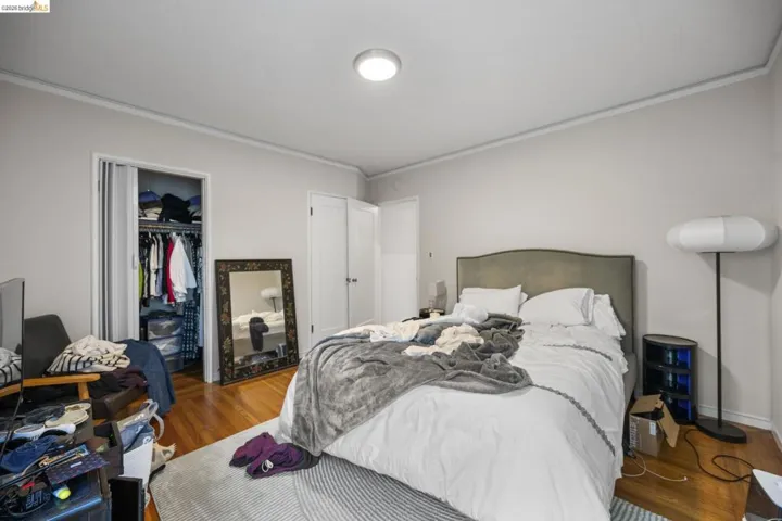 Bedroom featuring crown molding, wood finished floors, and a walk in closet