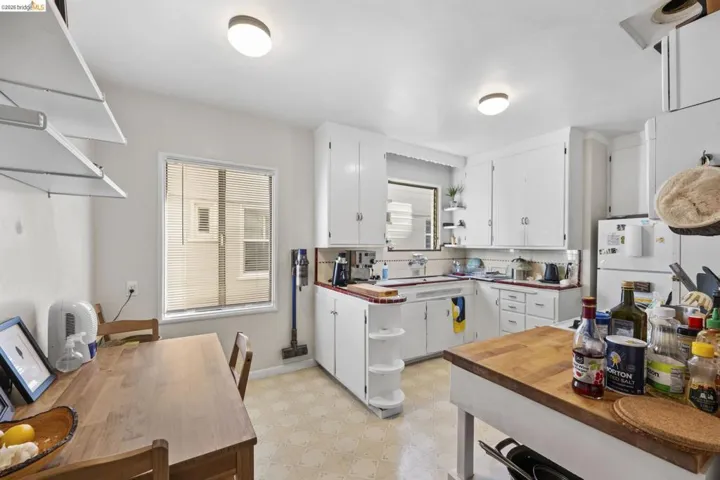 Kitchen featuring open shelves, light floors, white cabinets, tasteful backsplash, and wood counters