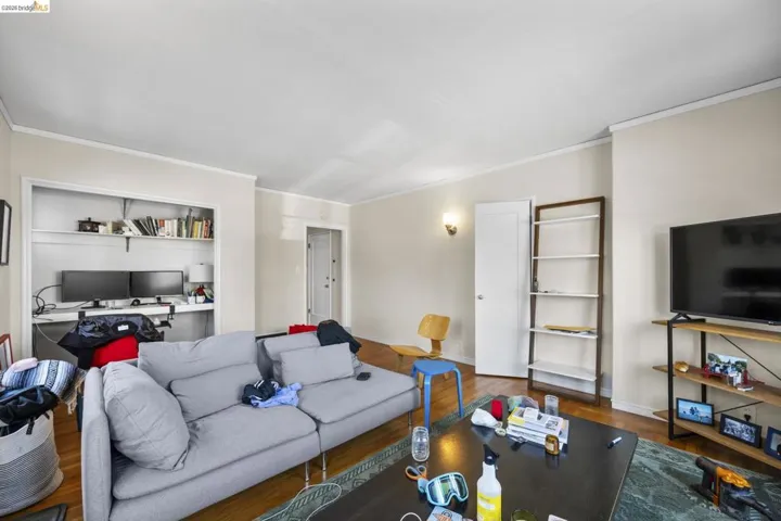 Living area with crown molding, wood finished floors, and an office area