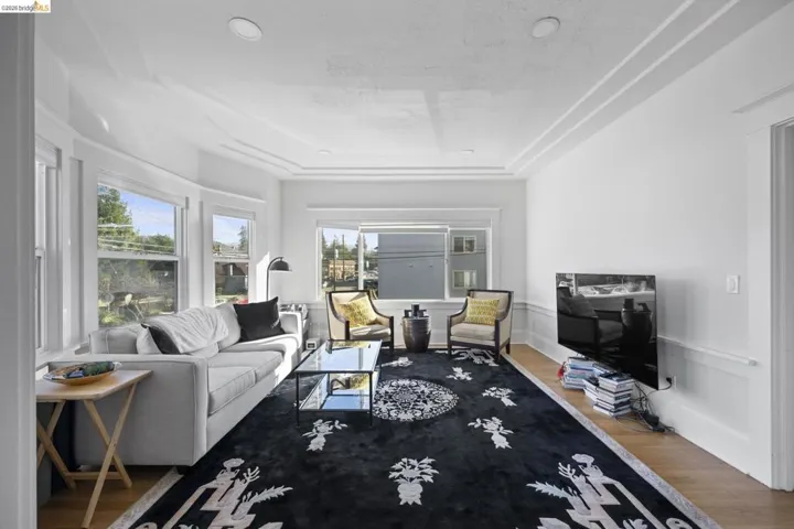 Living room featuring wood finished floors, a raised ceiling, and recessed lighting