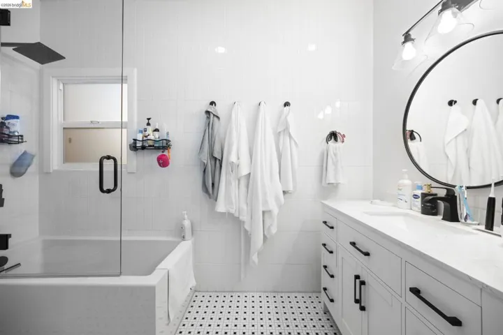 Bathroom with vanity, enclosed tub / shower combo, and tile walls
