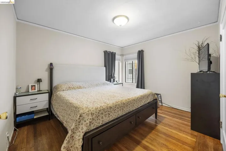 Bedroom with dark wood-style floors and crown molding