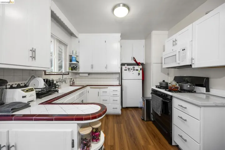 Kitchen featuring open shelves, white appliances, white cabinets, dark wood-type flooring, and tile counters