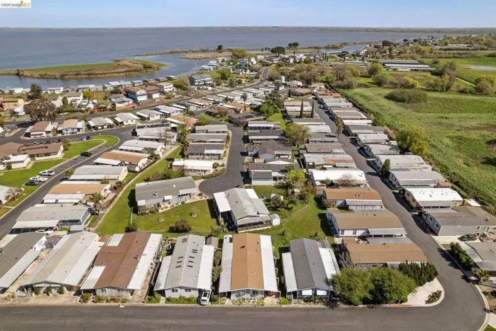 Aerial view of property and surrounding area featuring nearby suburban area and a large body of water