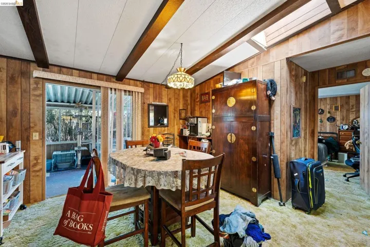 Dining area with light carpet, beamed ceiling, and wooden walls