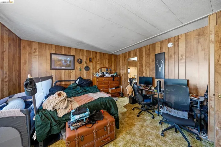 Bedroom with an office area, wood walls, and carpet flooring
