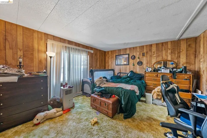 Carpeted bedroom featuring wood walls