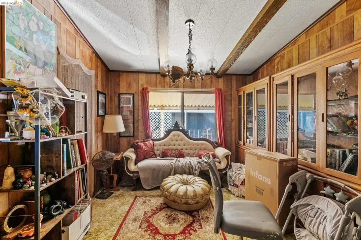 Bedroom with hanging lights, wooden walls, and light carpet