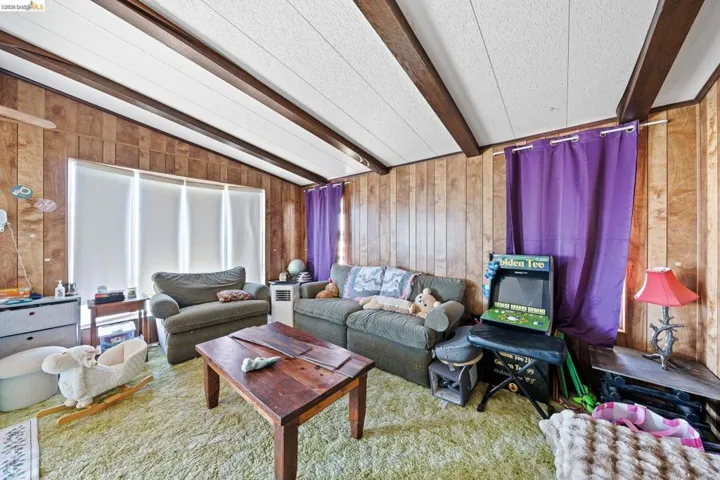 Living room with wood walls and vaulted ceiling with beams