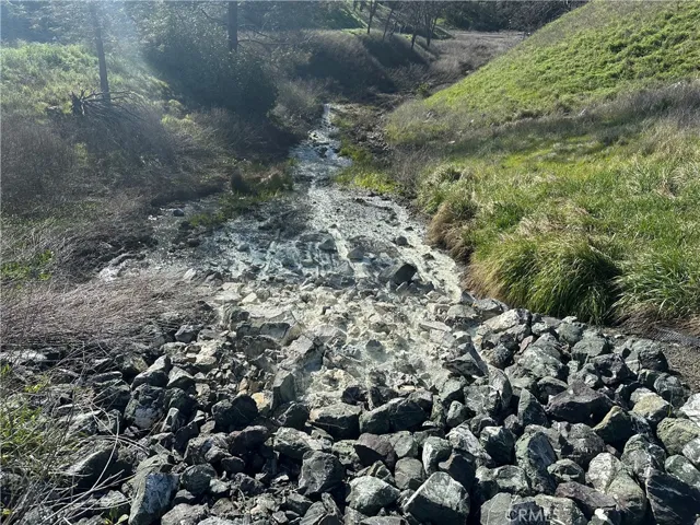 The spring runs under the road then cascades over some carefully placed cobbles. Minerals have built up over time to give the cobbles the white color.