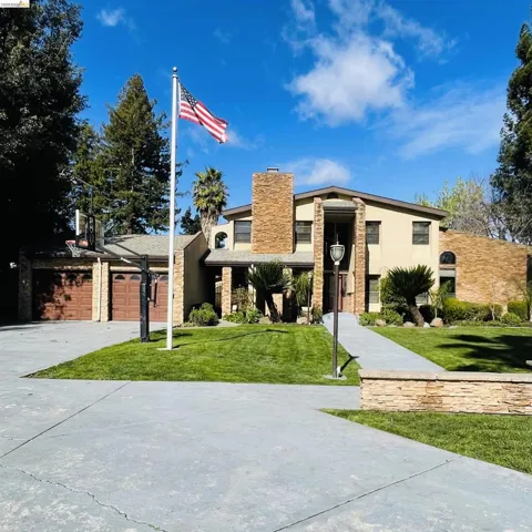 Mid-century home featuring driveway, a front lawn, stucco siding, and a chimney