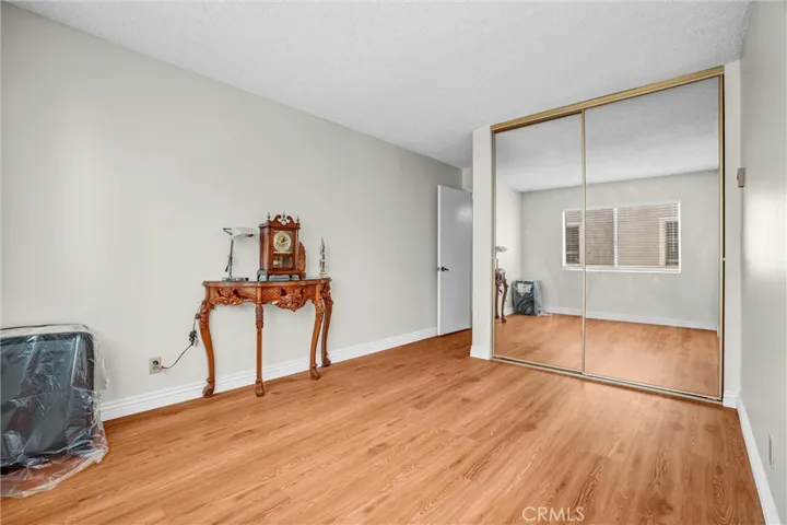 Spacious guest bedroom featuring a walk-in closet with mirrored doors, new laminate flooring, and fresh designer paint, creating a bright and comfortable living space.