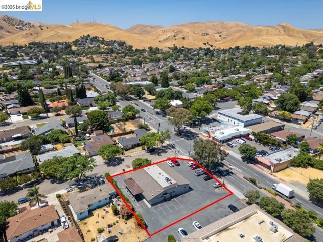 Aerial view of property and surrounding area with a mountain backdrop and property parcel outlined