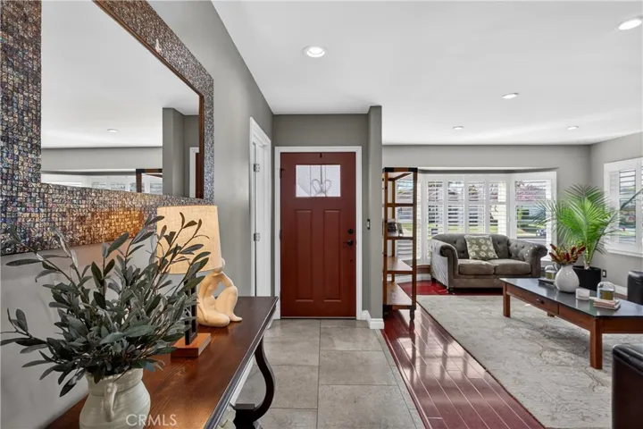 Tiled entry, large front living room with laminate wood flooring and recessed lighting, wood shutters too