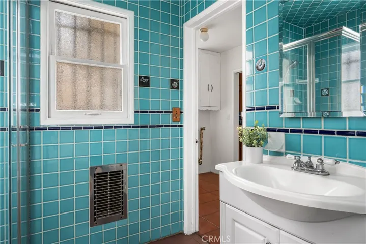 Attached primary bathroom with built-in heater and door to laundry room