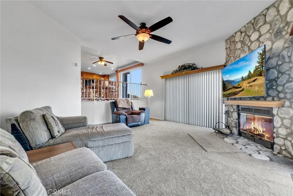 Family room with beautiful floor to ceiling rock fireplace and flat panel TV that is included with the home.