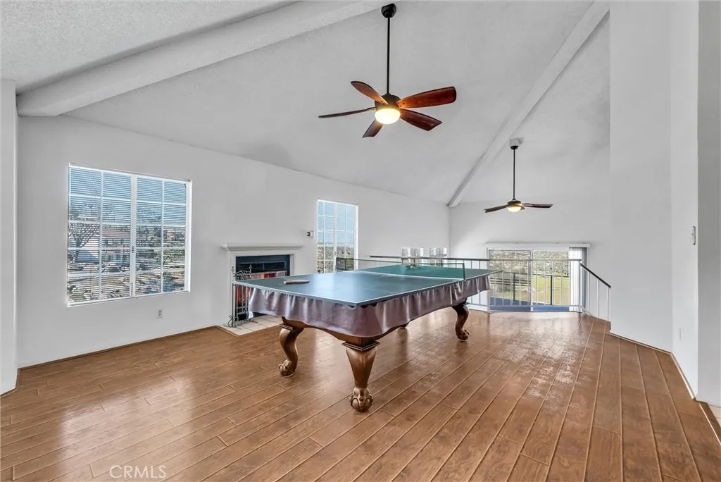 Living room used as a game room.  Attractive Pergo wood flooring.  Includes a fireplace and ceiling fan.