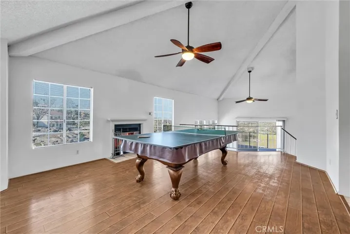 Living room used as a game room.  Attractive Pergo wood flooring.  Includes a fireplace and ceiling fan.