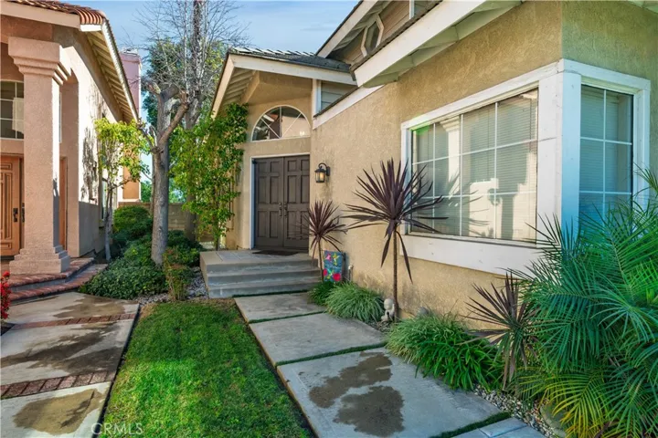 A private walkway leads to the double-door entry, framed by greenery and thoughtful landscaping.