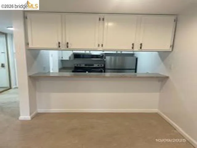 Kitchen with white cabinets, stainless steel appliances, and light countertops