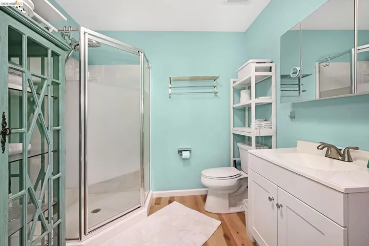 Full bath with a shower stall, vanity, and light wood-type flooring