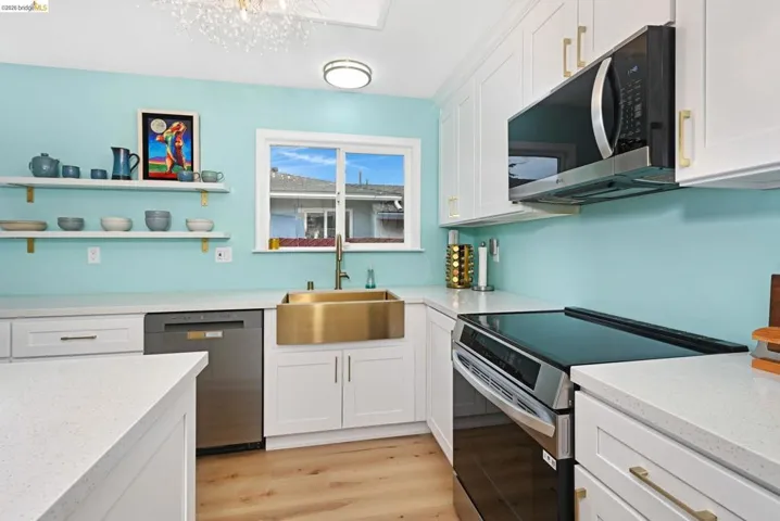Kitchen featuring stainless steel appliances, white cabinetry, and light stone countertops