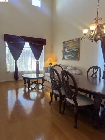 Vaulted ceilings with a high-set window, hardwood flooring, and an ornate chandelier