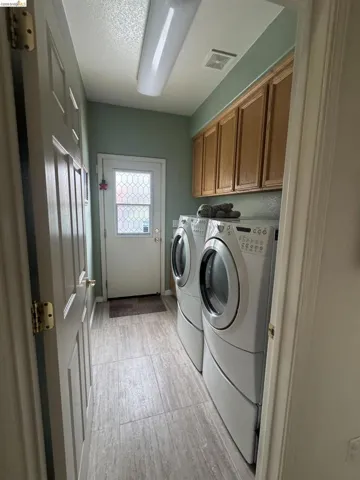 Dedicated laundry area featuring wood-finish tile flooring, upper cabinetry, and a door with a decorative glass insert