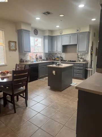 Kitchen featuring backsplash, a center island, gray cabinetry, dishwasher, and recessed lighting