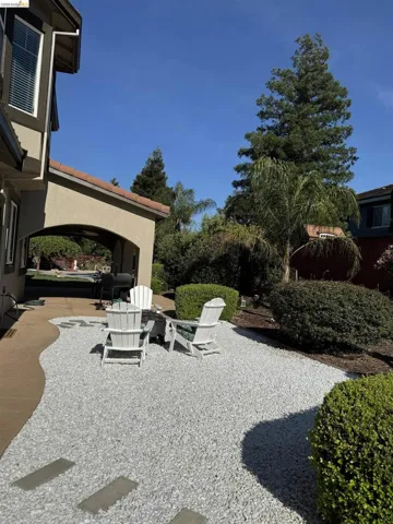 Outdoor patio featuring light grey gravel, concrete stepping stones, and a curved concrete path
